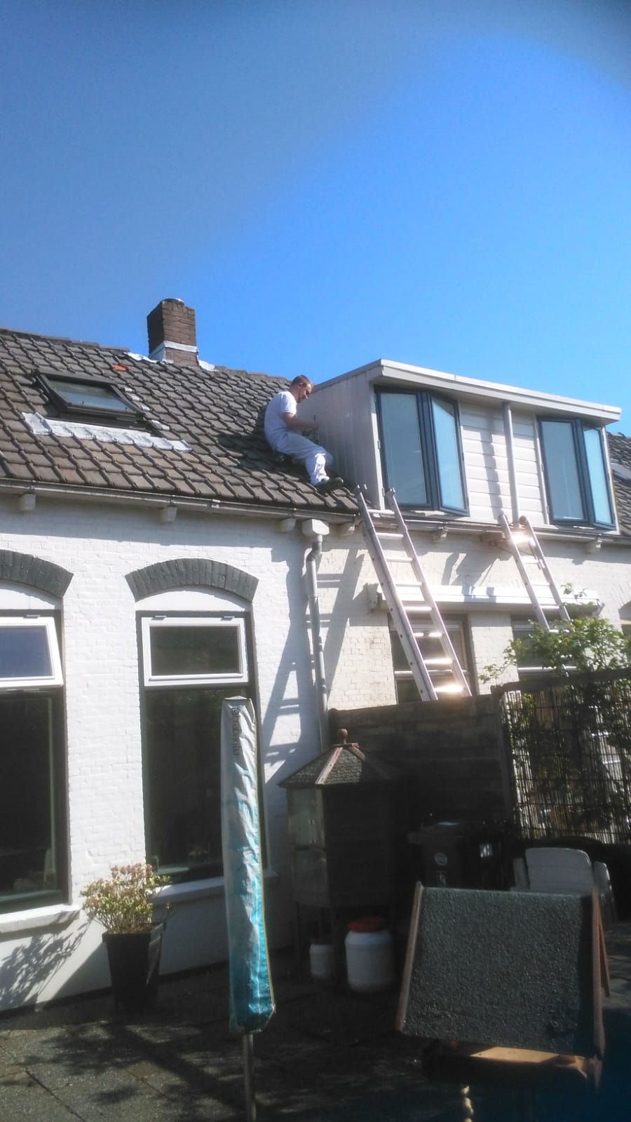 Buitenschilderwerk aan dak en dakkapel, ladders tegen de gevel