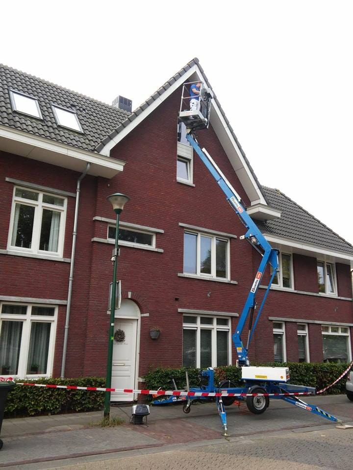 Hoogwerker bij de puntgevel van een bakstenen woning