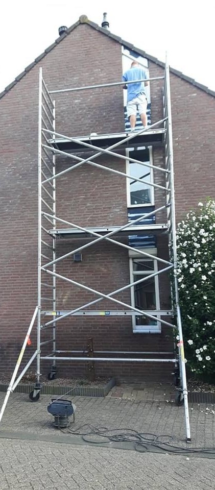 Rolsteiger tegen een zijgevel, schilder aan het werk bij het bovenste raam